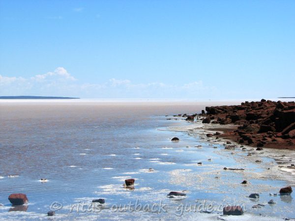 Glistening salt lake surrounded by red hills