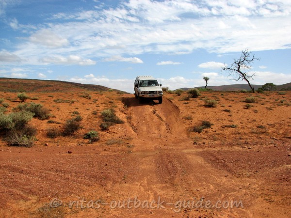 A car driving down into a dry creek bed